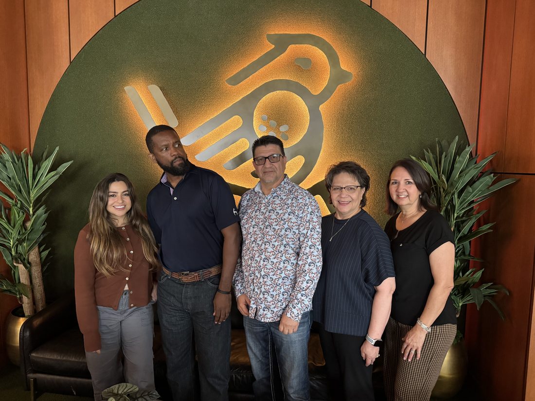 Austin District team members posing together in front of a lit bird sign